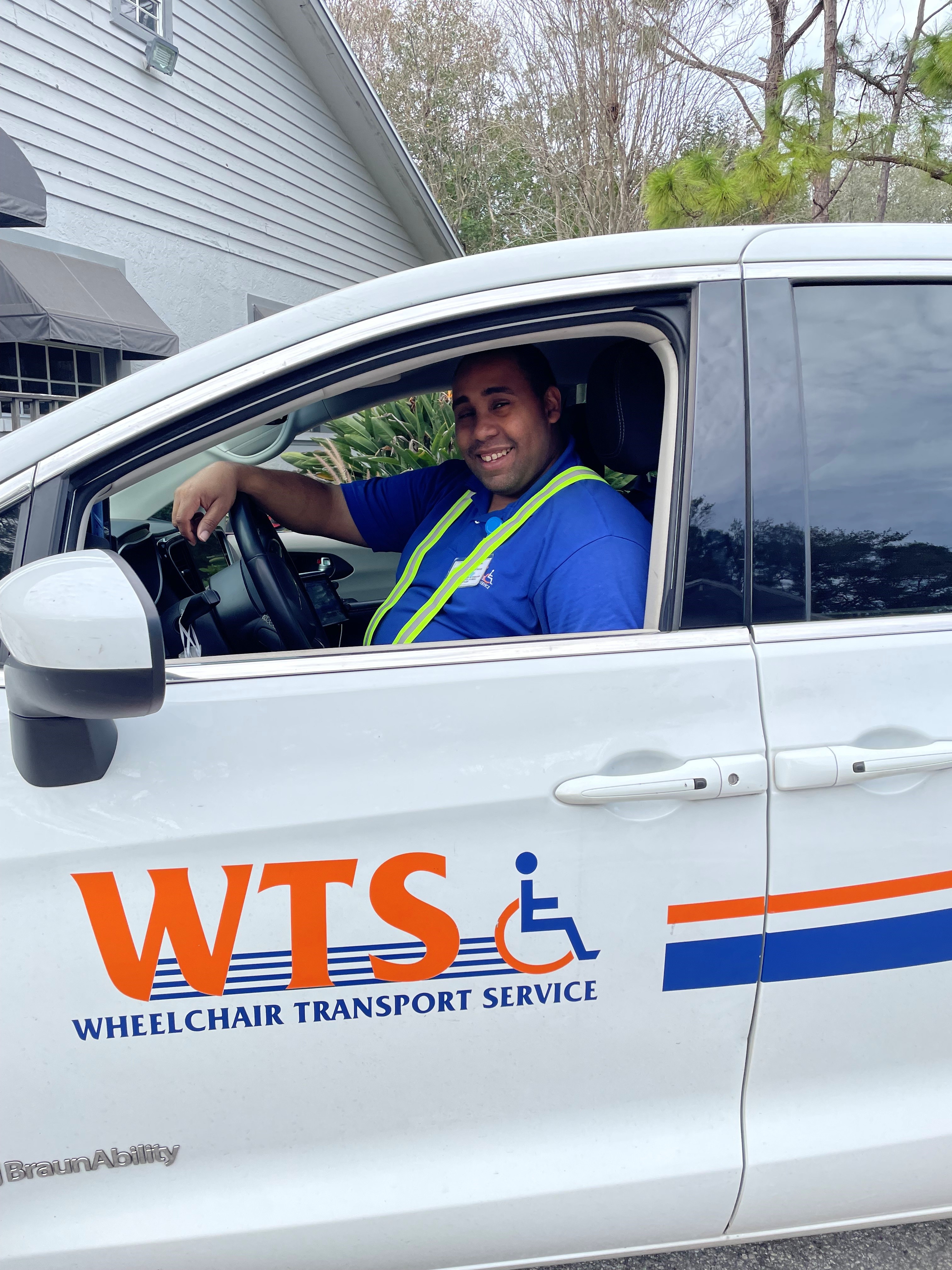 WTS driver smiling from the driver's seat of a wheelchair-accessible van